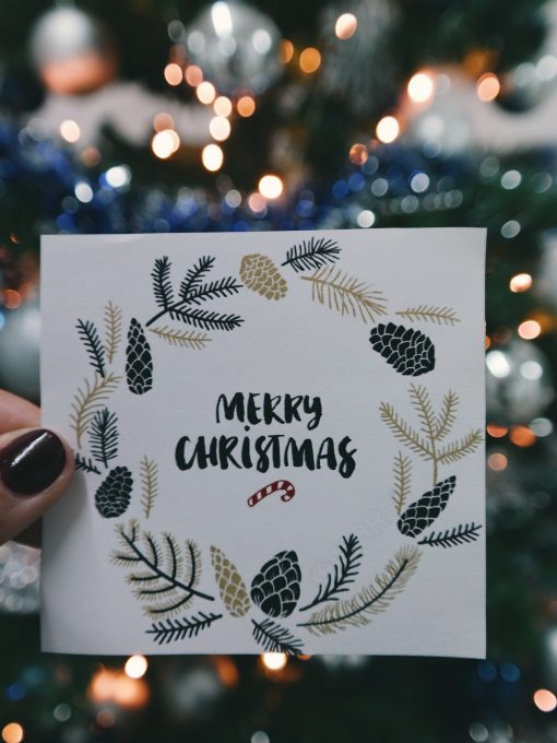 A person holding a beige and black floral Merry Christmas card