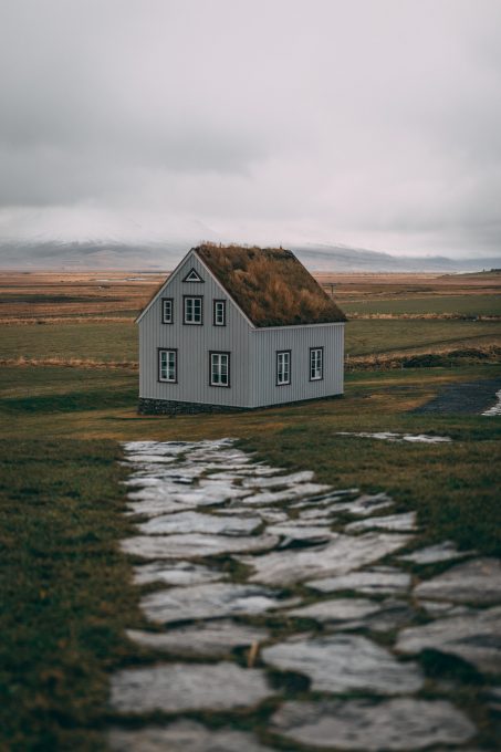 A turf house at a green field on a cloudy day