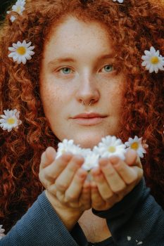 A woman with pierced nose holding daisies