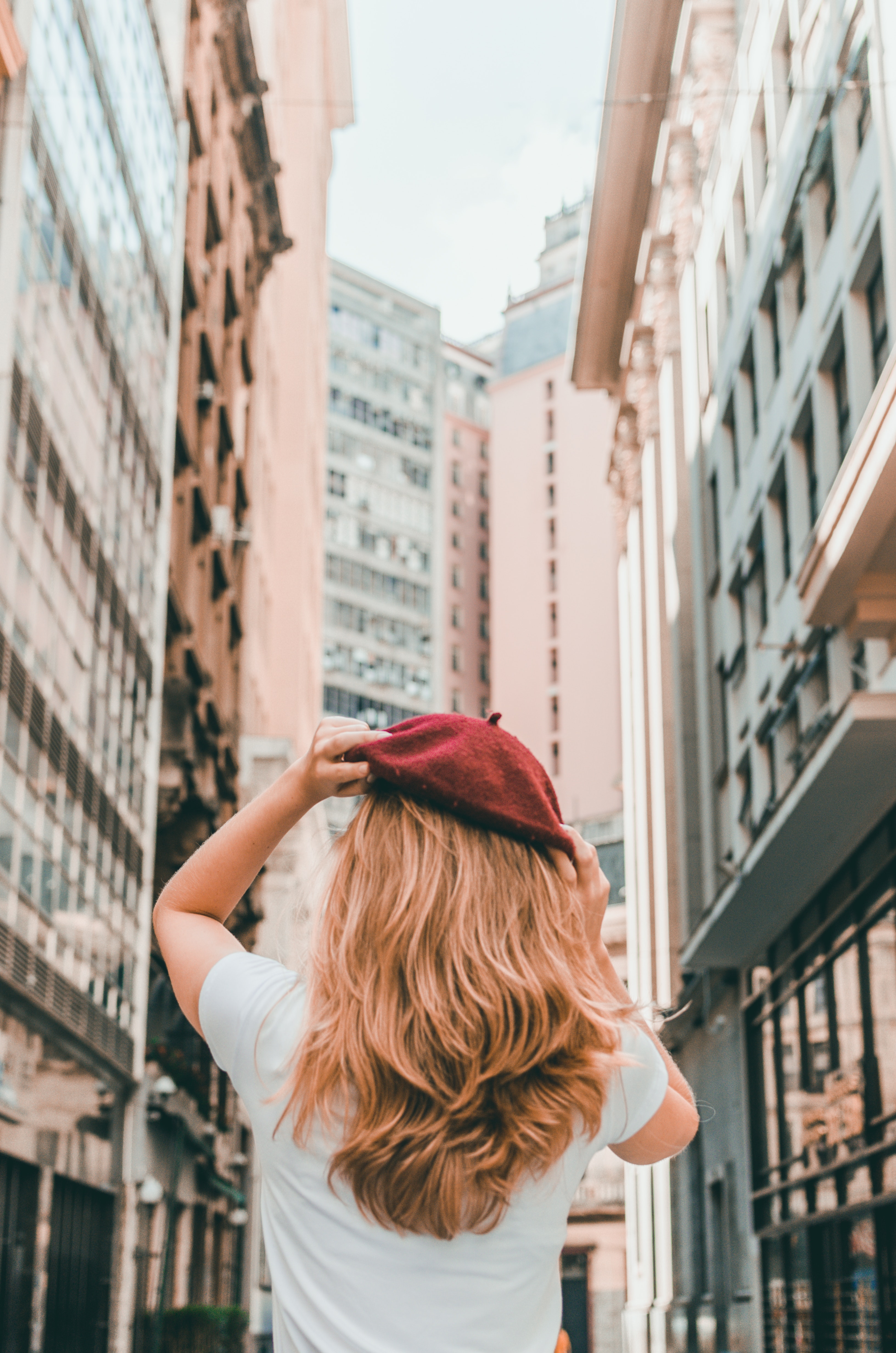 Back view of a girl in a red hat walking among tall buildings