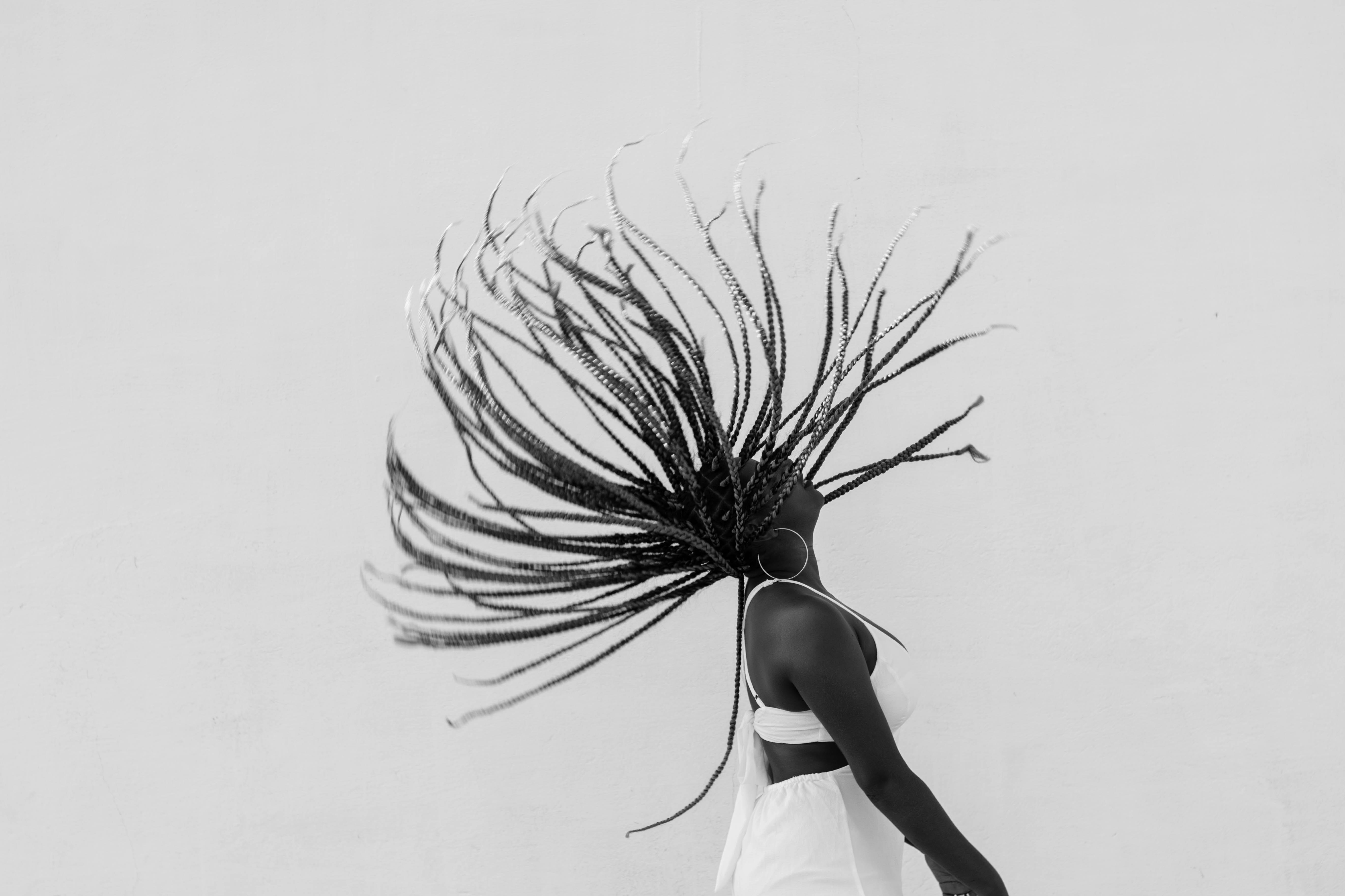 Black and white photo of a woman in a white dress throwing up her hair