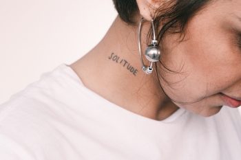 Close-up photo of a woman in a white t-shirt showing her neck tattoo