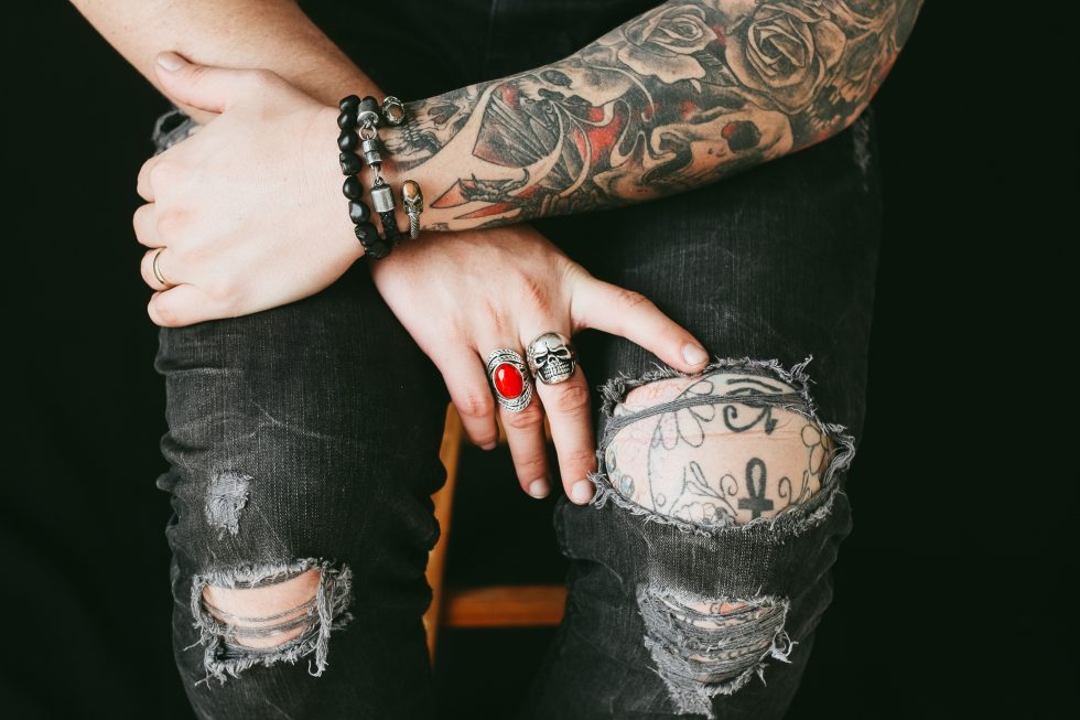 Photo of a tattooed person wearing ripped jeans