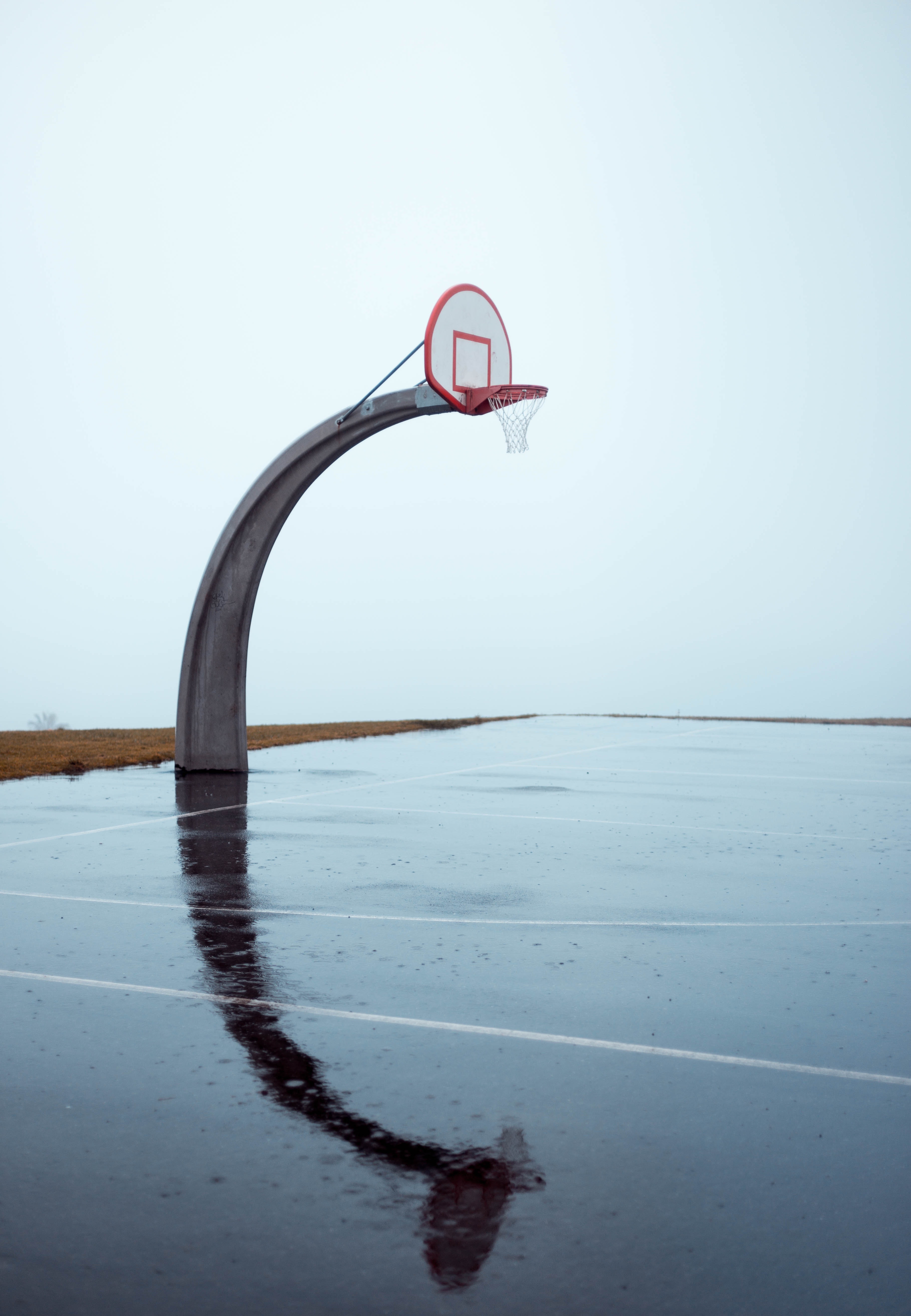 Photo of an empty concrete basketball court on a gloomy day