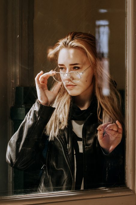 Portrait of a woman wearing a black leather jacket in front of a window