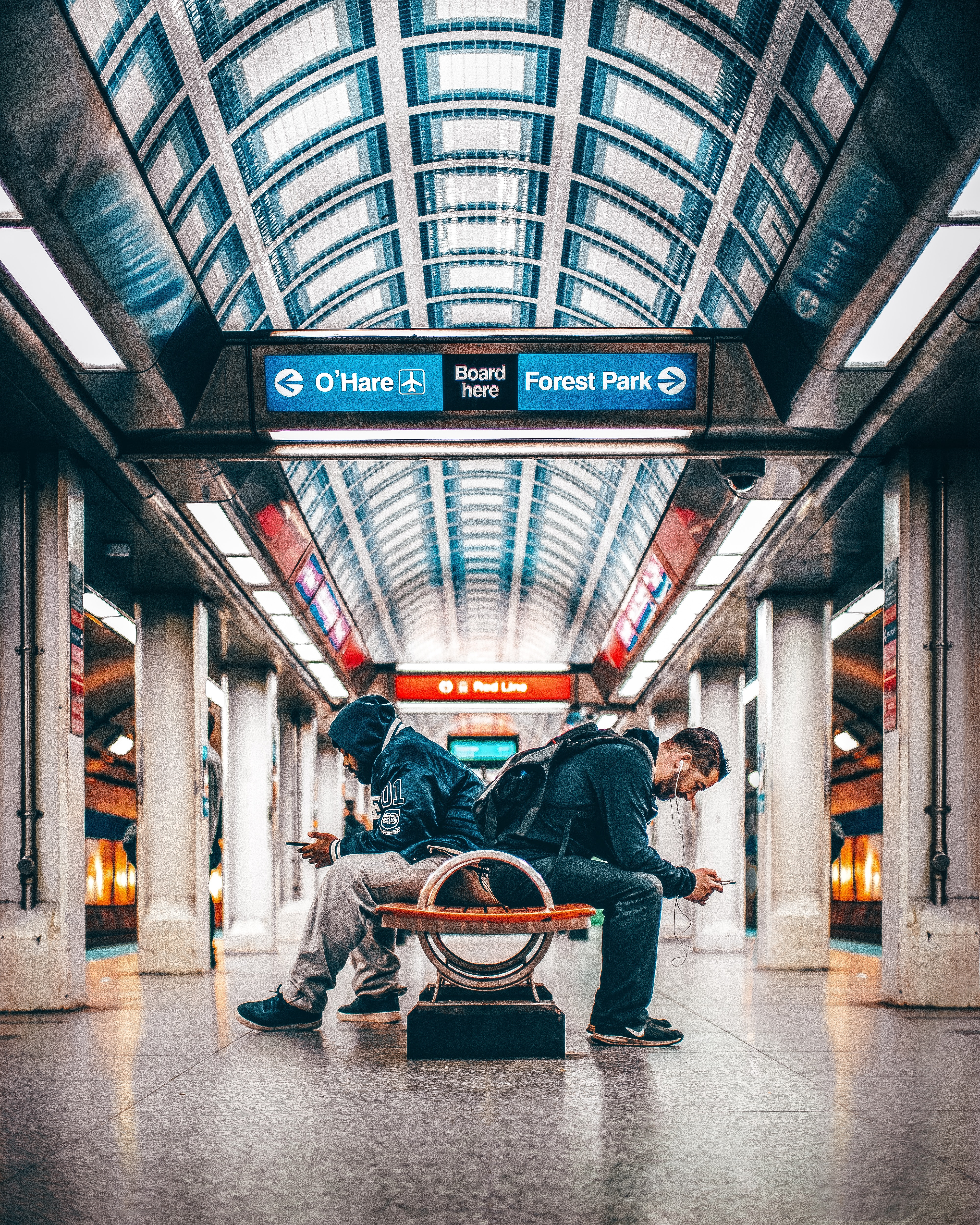 Two men sitting on a bench inside a station