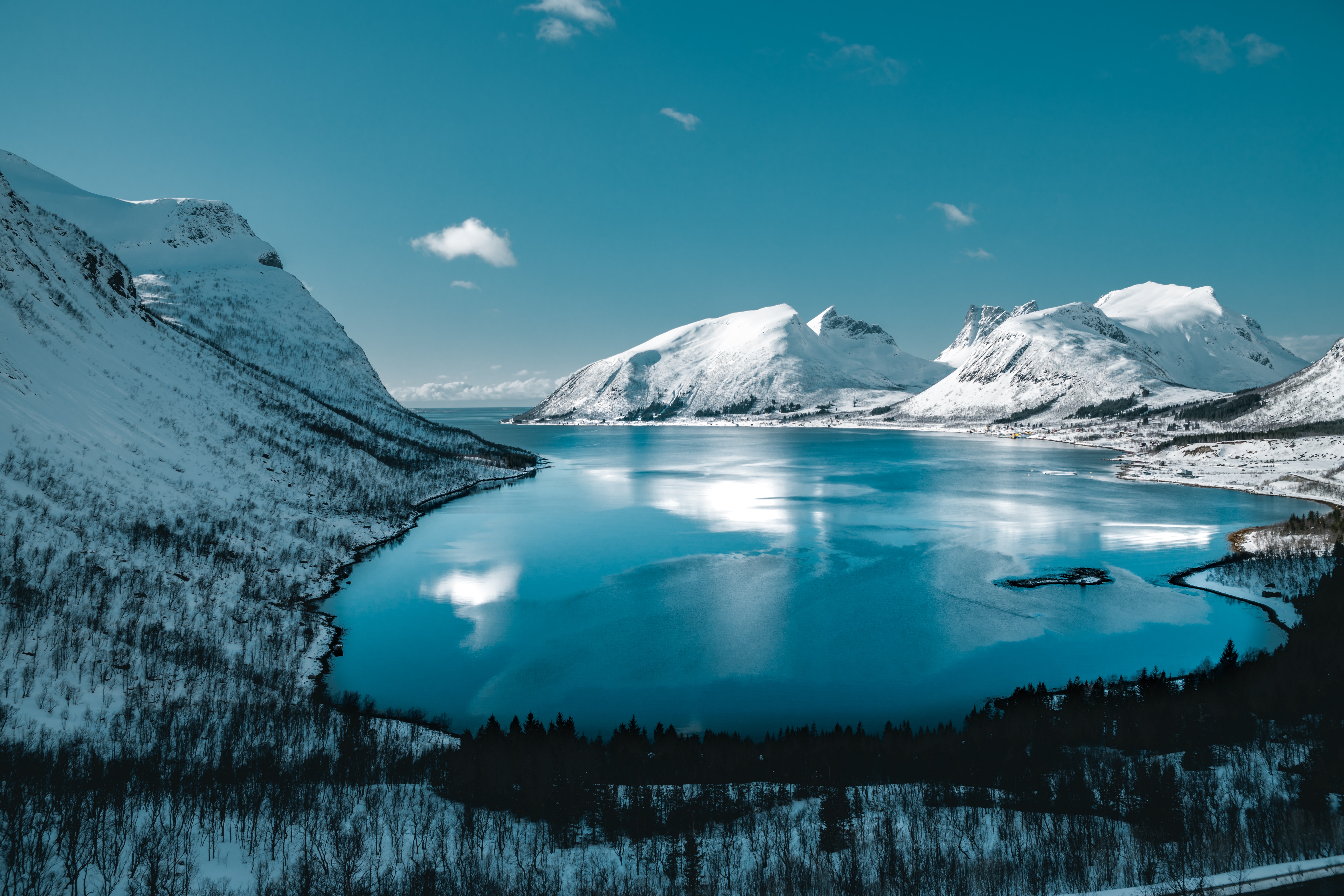 A lake surrounded by snow-covered mountains under a blue sky