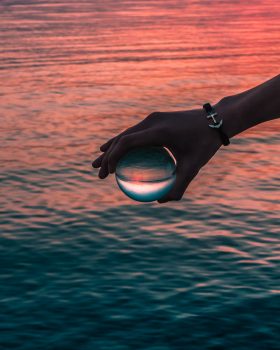 A person holding a round glass ball over the water