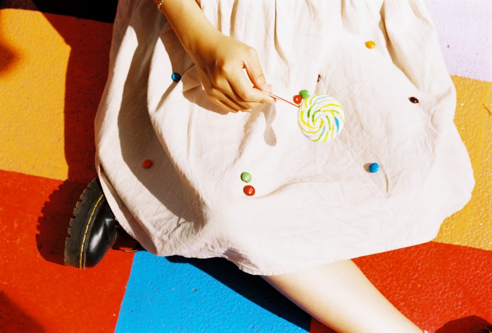 A person sitting on the colorful floor holding a lollipop