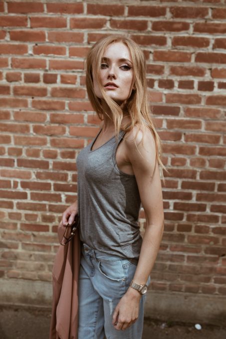A woman wearing a grey tank top and denim jeans