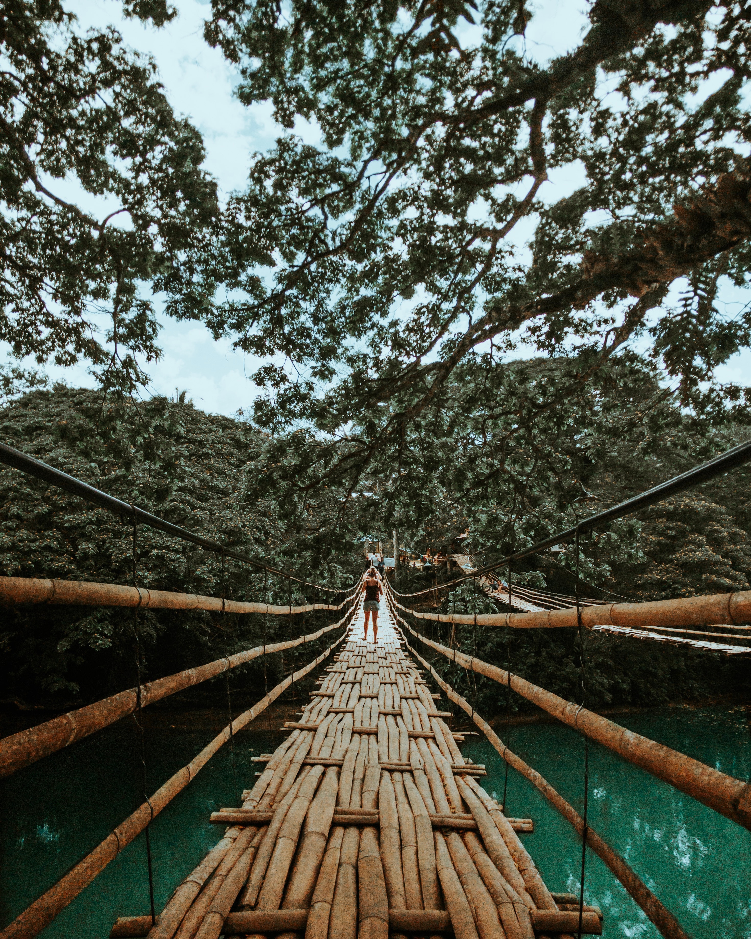 Back view photo of a woman standing on a wooden bridge