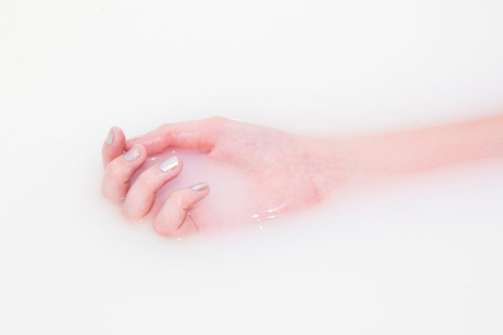 Right hand of a person lying in a milk bath
