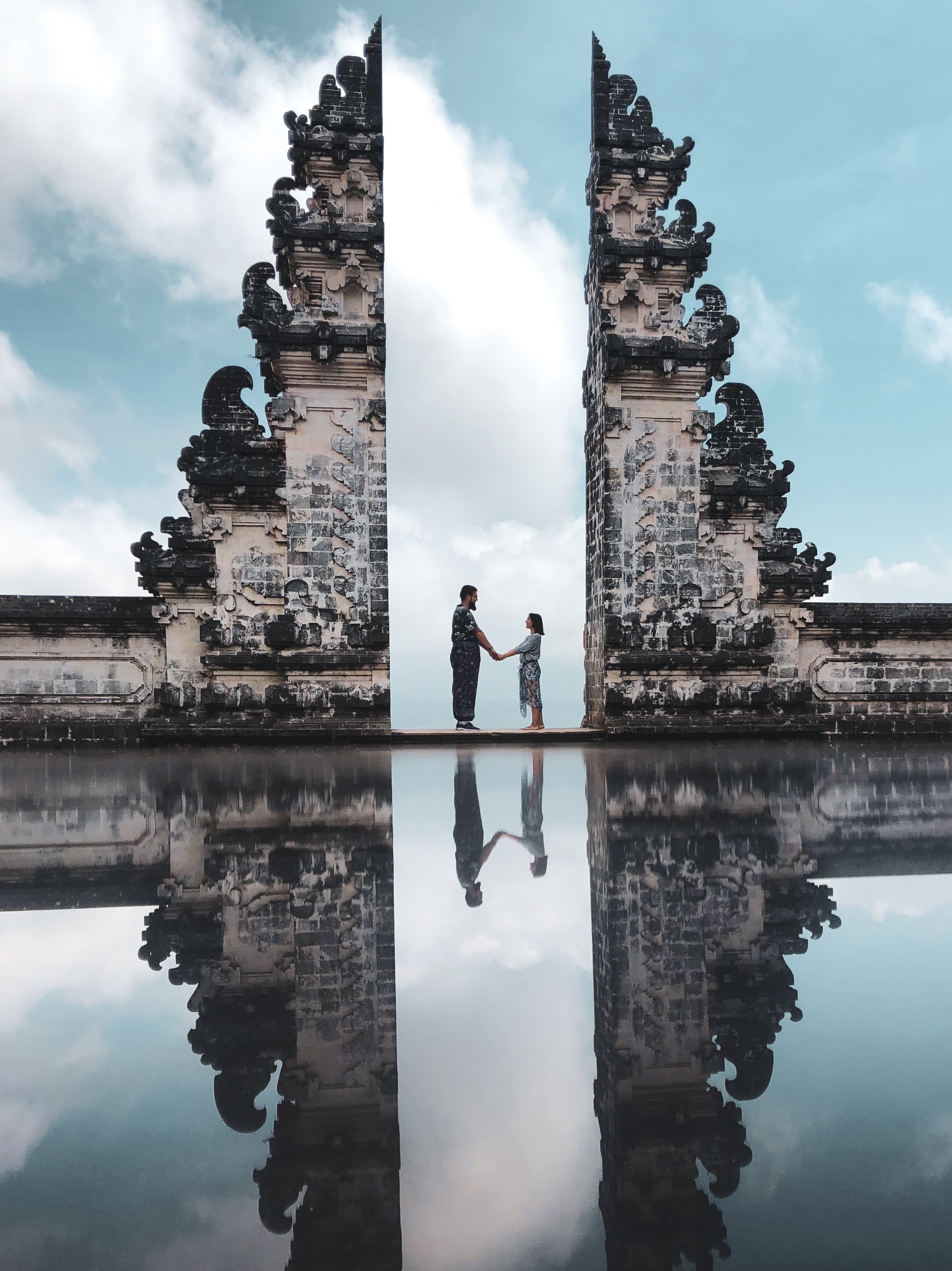A couple in between of ancient ruins with water reflection