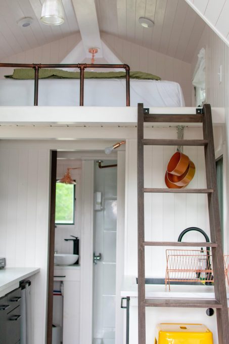 A room with a ladder and a bed